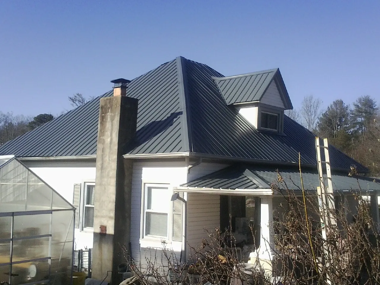 Dark blue standing seam metal roof on a white farmhouse with dormer — Slate & Tile Roof Repair by Roofing Brothers in San Pedro