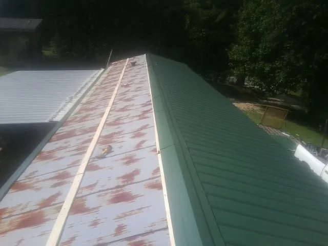Old rusted panels beside newly installed green metal roofing — Wind Damage Roof Repair by Roofing Brothers in San Pedro