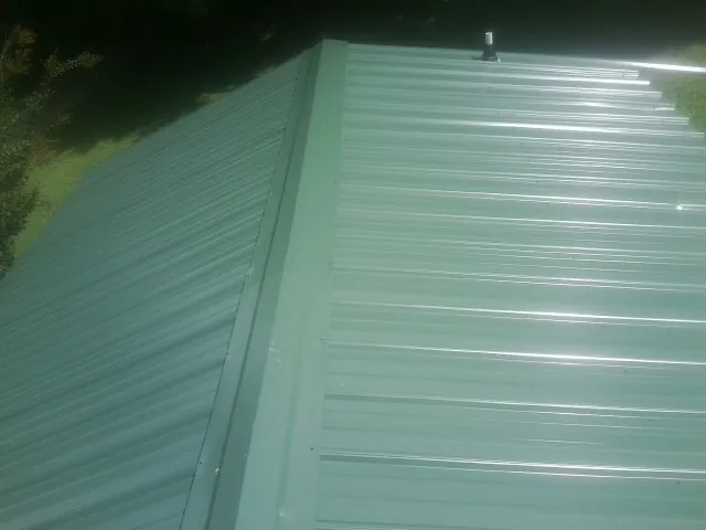 New green metal panels meeting at the ridge of a roof — Flat Roof Repair work by our crew in San Pedro