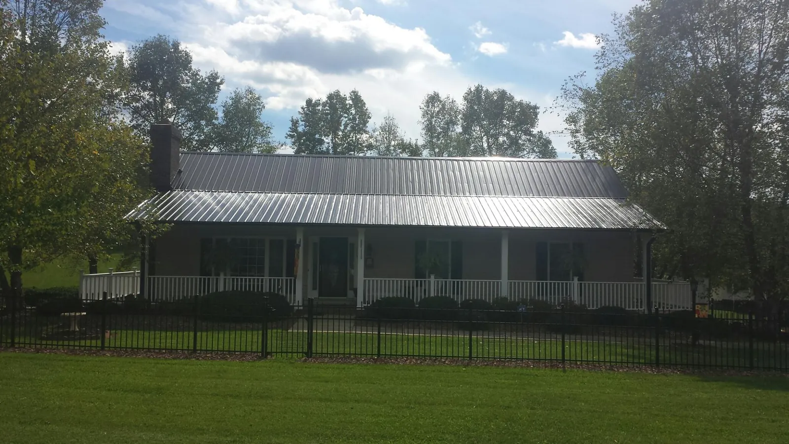 Gray metal roof on a brick ranch with a full width front porch — Gutter Guard Installation work by our crew in San Pedro