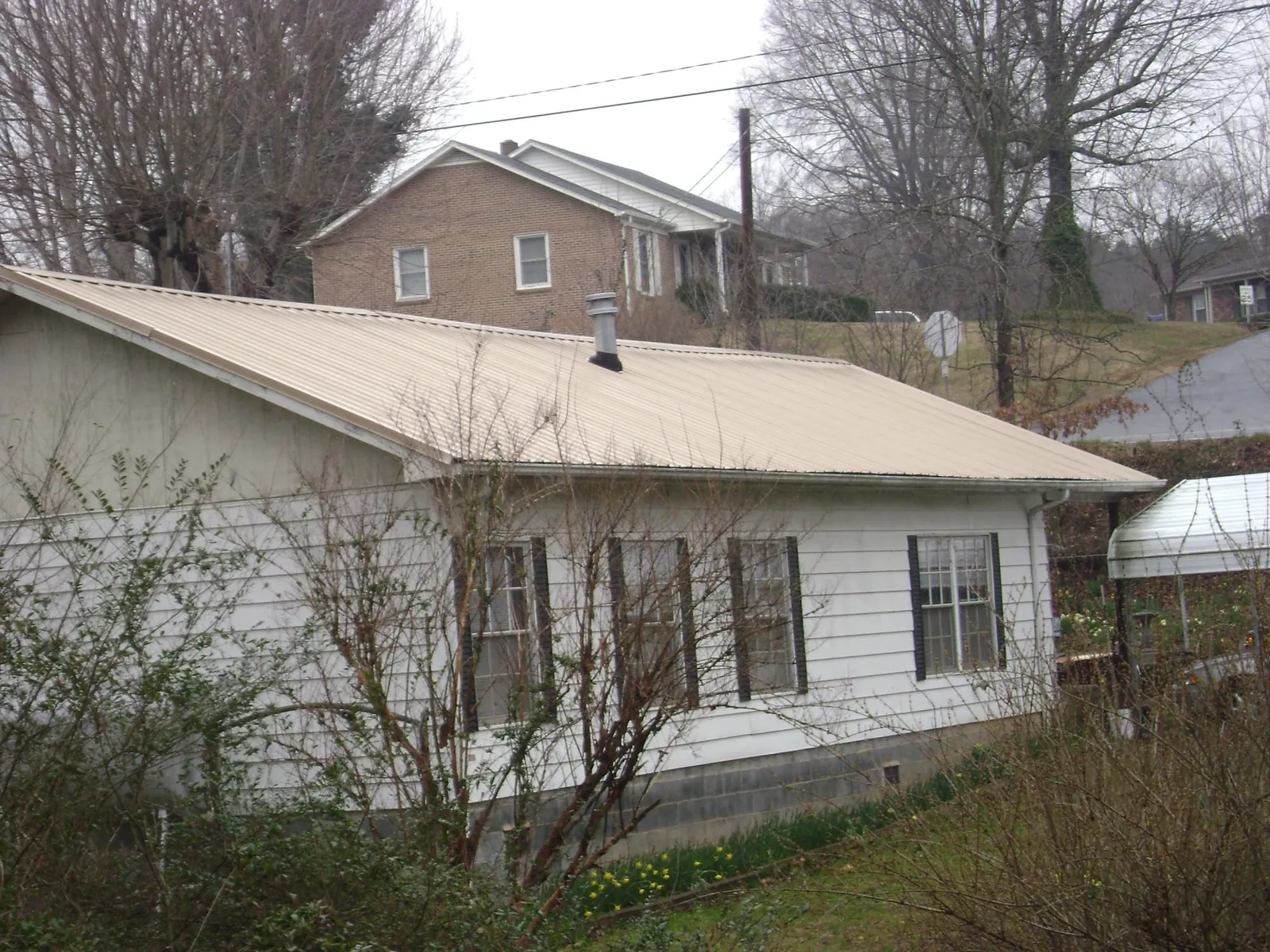 Tan metal roof on a white sided house set into a hillside — Commercial Roofing by Roofing Brothers in San Pedro
