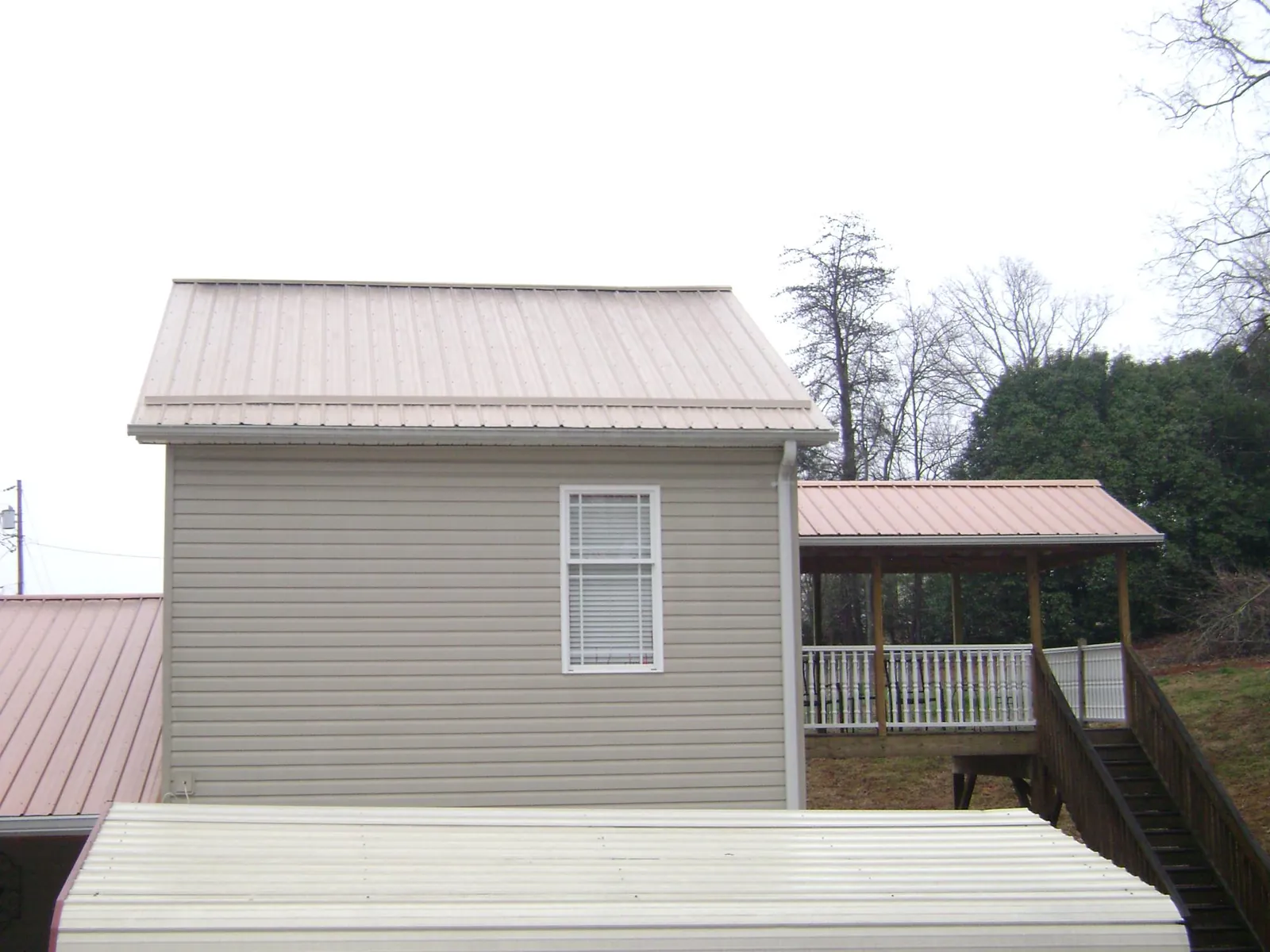 Tan metal roofs on a two story addition and attached porch, from a Roof Replacement job in San Pedro