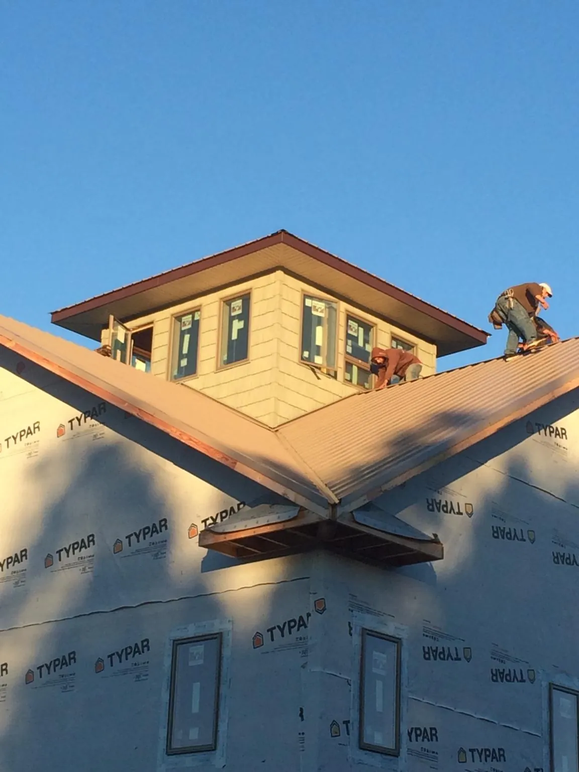 Roofers working around a rooftop cupola on a new metal roof at sunset — Roof Waterproofing in San Pedro by Roofing Brothers
